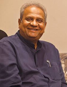 Bhupesh R. Patel seated, in a dark blue kurta